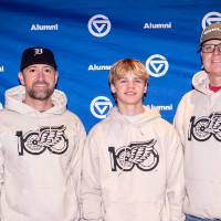 Group of three in their custom sweatshirts in front of GVSU backdroup